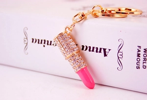 Macro shot of gold lipstick keychain with sparkling rhinestones and pink enamel finish