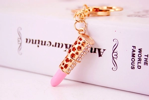 Macro detail of a lipstick-shaped keychain with gold alloy and pink rhinestone crystals