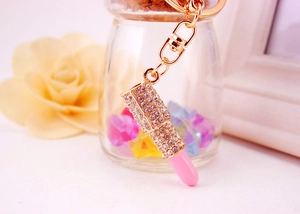 Detailed view of lipstick keychain featuring sparkling crystals and a pink metallic tip