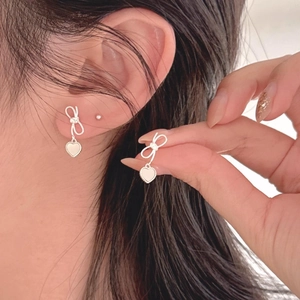 Elegant 925 silver bow stud earrings with heart shell pendant on model ear