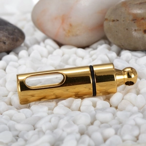 Macro shot of gold stainless steel perfume bottle pendant on smooth river stones