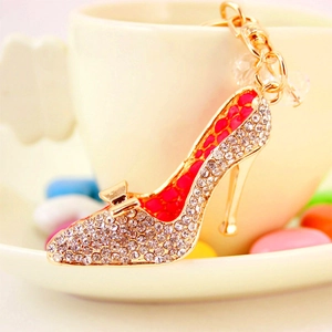 Porte-clés chaussure à talon en cristal doré et rouge posé sur une assiette blanche