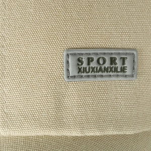 Close-up of khaki canvas baseball cap with grey rectangular SPORT and XIUXIANXILIE patches