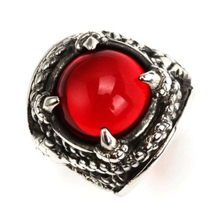 Macro shot of silver dragon claw ring holding a round red gemstone on white background