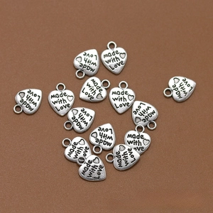 Detalle macro de colgantes de corazón con grabado 'Made with Love' para creación de joyas