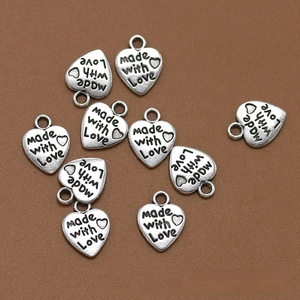 Primer plano de dijes de corazón plateados vintage con grabado 'made with Love'