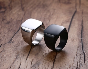 Detailed view of square silver and black stainless steel rings on a wood background