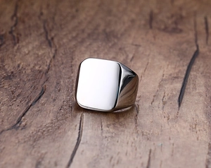 Macro shot of silver square signet ring for men on wood surface with polished finish