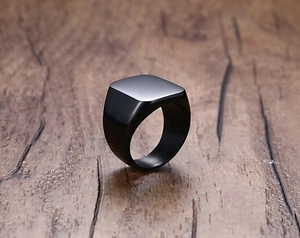 Macro shot of a black square signet ring for men on a wooden background