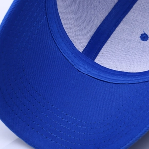 Detail view of the deep blue baseball cap showing cotton twill fabric and reinforced brim