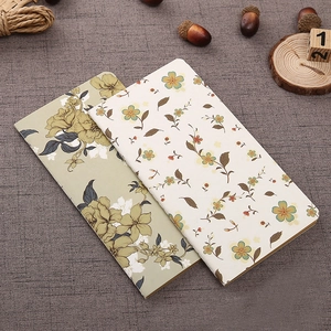 Close-up of vintage floral patterns on kraft paper notebooks with linen background