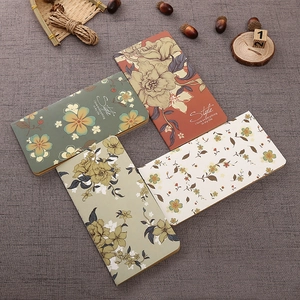 Vintage floral kraft paper notebooks in green, terracotta, and beige on grey fabric