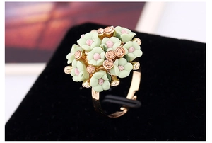Macro shot of floral resin cluster ring with pink and green petals on gold band