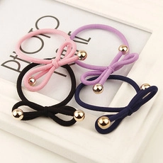 Detail of four colorful bow elastic hair ties with gold beads in a white photo frame