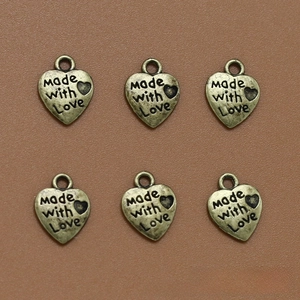 Detalle de seis colgantes de corazón de bronce grabados con Made with Love para joyas