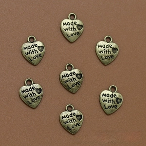 Vista detallada de colgantes de corazón en bronce con grabado Made with love para joyas DIY