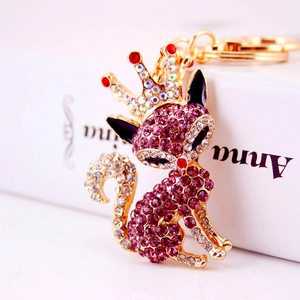 Porte-clés renard doré avec strass violets et détail de couronne sur un livre