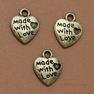 Detalle macro de colgantes de corazón en bronce antiguo grabados con Made with love para DIY