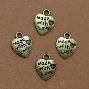 Detalle de colgantes de bronce en forma de corazón con grabado Made with Love para joyas