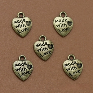 Detalle macro de cinco dijes de corazón en bronce antiguo con grabado Made with Love para DIY