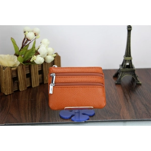 Detailed view of orange genuine leather coin purse with triple zippers on wood background