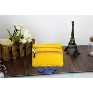 Detail view of yellow litchi leather coin purse with triple zippers on a blue display stand
