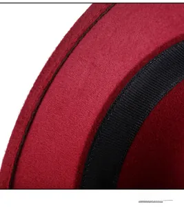 Macro detail of red wool felt hat with black grosgrain ribbon and precise stitching