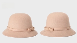 Detailed side view of two elegant cream wool felt cloche hats with decorative ribbon bows