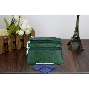 Three-layer green pebbled leather coin purse with silver zippers on a wooden table