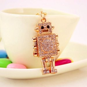 Sparkling robot keychain with rhinestones and gold-plated metal on cream saucer