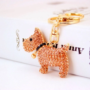Creative puppy keychain with champagne gold rhinestones and bell on a white book