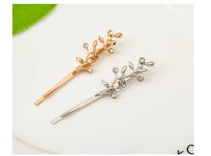 Detailed close-up of gold and silver leaf hair clips with rhinestones on white tray