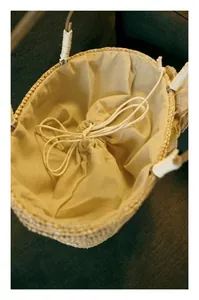 Detailed view of the straw handbag showing the cotton lining and drawstring closure