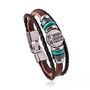 Detail of multi-layer braided leather bracelet with vintage metal anchor and coin charm