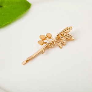 Elegant gold leaf and berry hair clip with polished mirror finish on white background