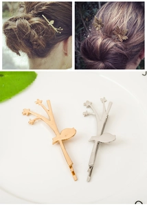 Detailed view of elegant gold maple leaf and bird hair pins on a white tray
