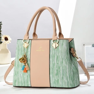 Detail view of green striped fabric and beige leather handbag with tassel and logo charm