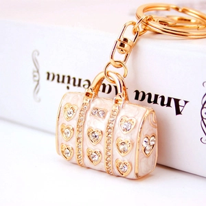 Chic gold handbag keychain with white enamel and heart rhinestones on vintage book background