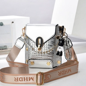 Detail of silver crocodile pattern mini bag with decorative bear charm and wide strap