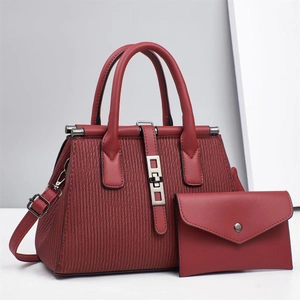Detailed view of dark red pleated handbag with silver metal rings and matching envelope pouch