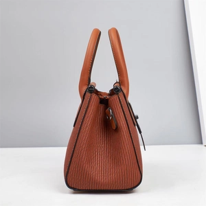 Detail of caramel brown handbag showing vertical pleated texture and dual handles