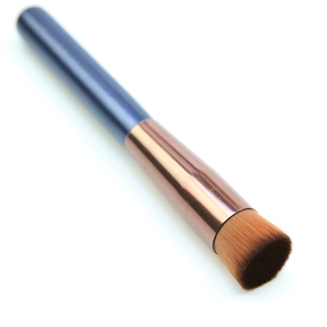 Close-up of small flat top concealer brush with blue handle and rose gold ferrule