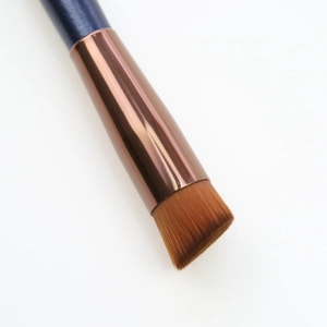 Macro shot of dense brown bristles and polished rose gold ferrule on a flat concealer brush