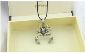 Macro shot of silver scorpion pendant with vintage punk details on a black cord