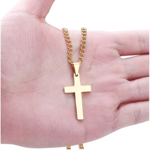 Detailed view of simple polished gold cross pendant held in hand for size scale