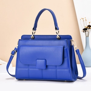 Sac à main élégant en cuir bleu matelassé avec poignée et finitions dorées sur fond neutre