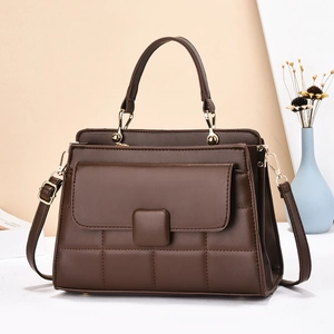 Sac à main en cuir marron foncé matelassé avec poignée et bandoulière dorée sur table