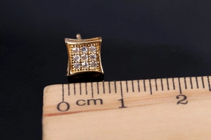 Macro view of square gold stud earring with 3x3 pave zircon inlay measured on ruler
