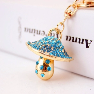 Sparkling blue rhinestone mushroom keychain with gold plating on a white book background
