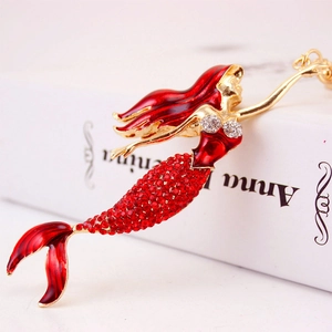 Sparkling mermaid keychain with red rhinestones and golden metal on Anna Karenina book